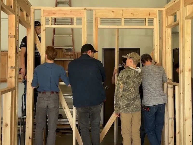 Students framing a wall with lumber inside the shop.